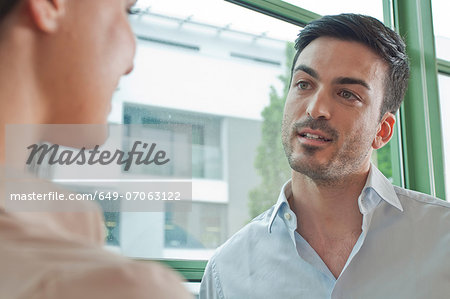 Two young colleagues having flirtatious meeting in office