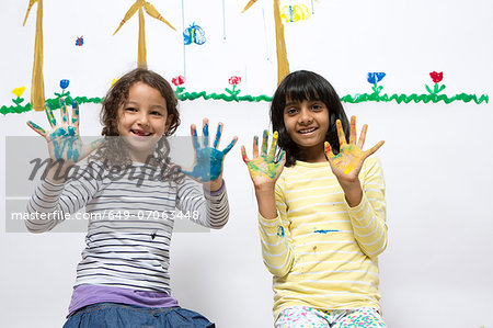 Two girls kneeling on floor with painted hands