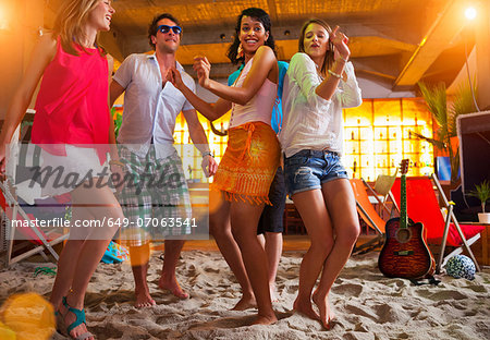 Friends dancing on sand at indoor beach bar