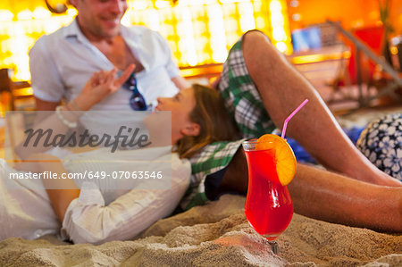 Young couple lounging on sand at indoor beach party