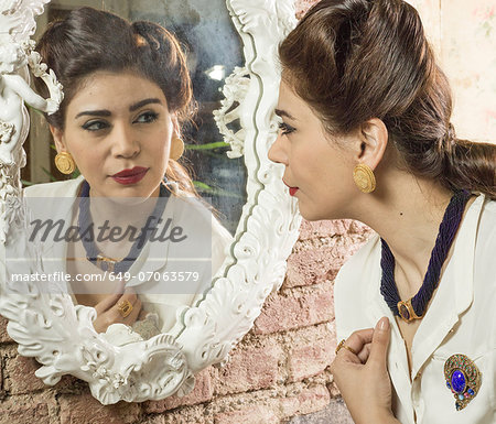 Woman in vintage clothes looking in mirror