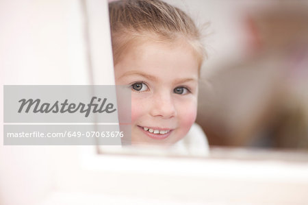 Close up of young girl looking through window at ballet class