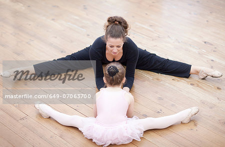 Teacher and young ballerina practicing stretch