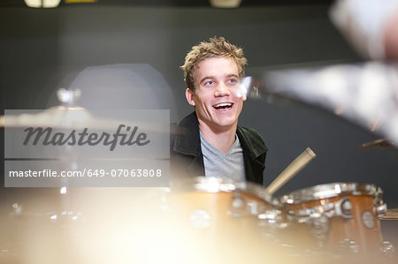 Young male playing drum kit in music store