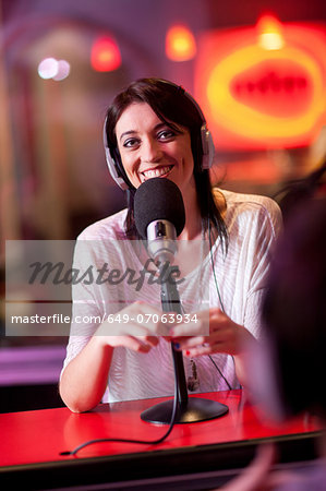 Mid adult woman broadcasting in recording studio