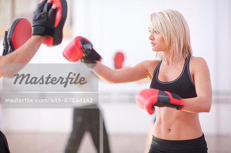 Young woman and trainer boxing in gym