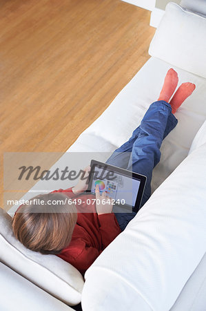 Boy on sofa using digital tablet