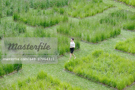 Young office worker strolling through grass maze