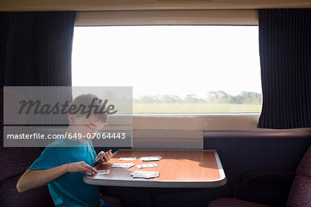 Young boy with playing cards on train