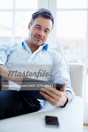 Man sitting on sofa using digital tablet Man sitting on sofa using digital tablet