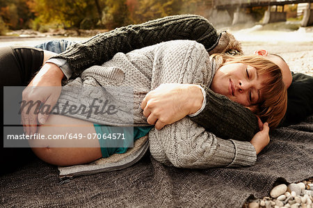 Pregnant woman and partner lying beside river