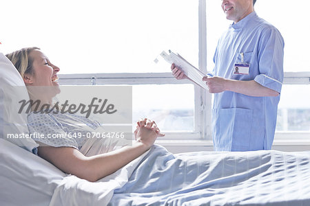 Patient lying in hospital bed laughing with nurse Patient lying in hospital bed laughing with nurse