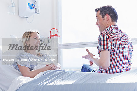 Patient lying in hospital bed talking to visitor