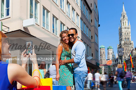 Woman photographing couple in Munich Marienplatz, Munich, Germany