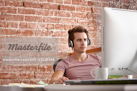 Young man using computer wearing headphones