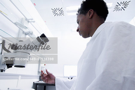 Scientist wearing lab coat using microscope