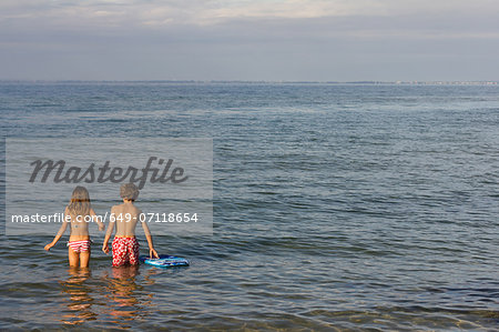 Brother and sister paddling in sea