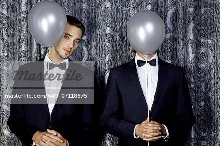 Two young men hiding behind balloons