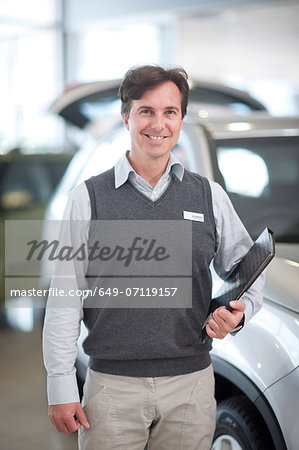 Car salesman with file in showroom