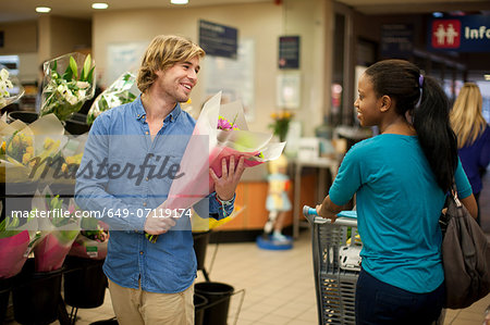 Young man selecting bunch of flowers whilst shopping