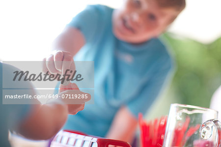 Two young sisters behind stall selling drink to cousin