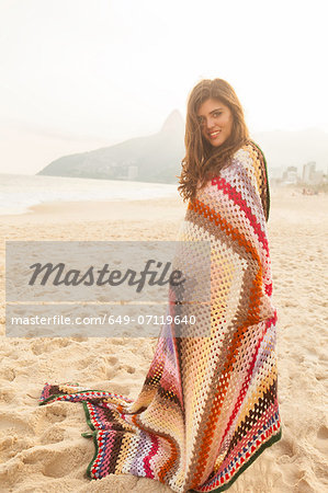 Young woman wrapped in blanket,  Ipanema Beach, Rio de Janeiro, Brazil