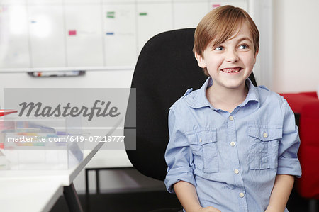 Boy wearing blue shirt on office chair