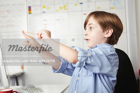 Boy playing with elastic band in office Boy playing with elastic band in office