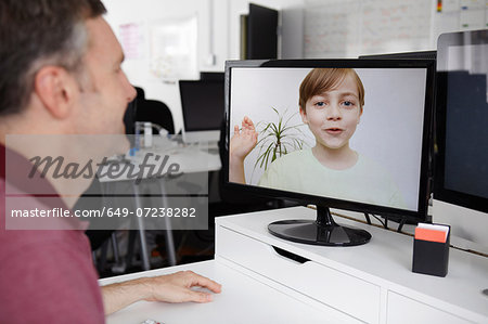 Man sitting at desk having video call with son