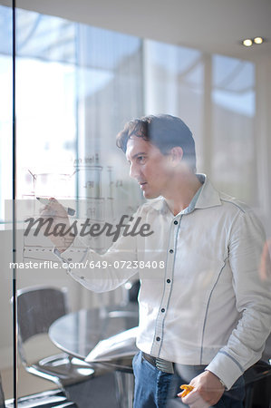 Man drawing architectural plans on glass wall