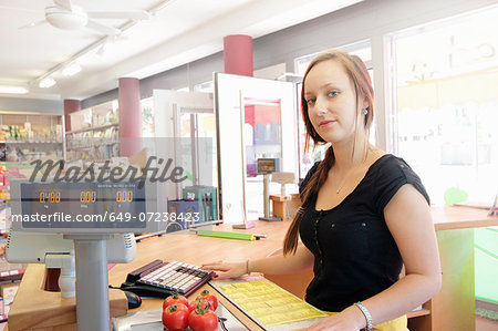 Woman working in organic food market, serving at cash register