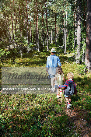 Father and daughters walking through forest