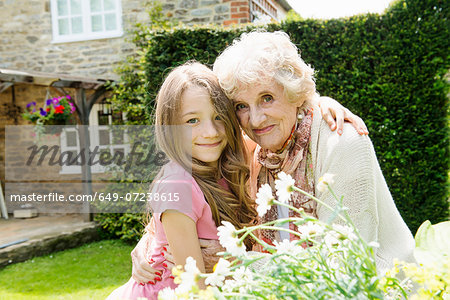 Portrait of grandmother and granddaughter with arms around each other