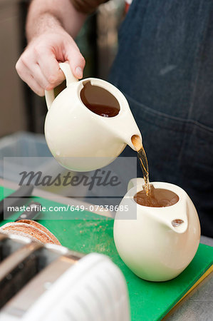 Barista pouring tea into teapot with ice