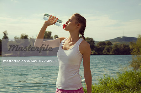 Young female jogger drinking bottled water