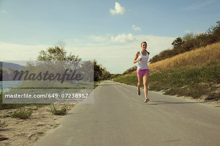Young female jogger running along riverside Young female jogger running along riverside