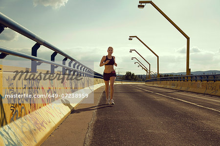 Young female jogger running on bridge Young female jogger running on bridge