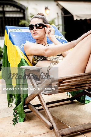 Young woman on hotel lounger wearing sunglasses