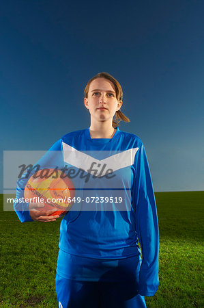 Portrait of female footballer holding ball