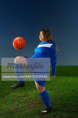 Female footballer playing keepy uppy with ball