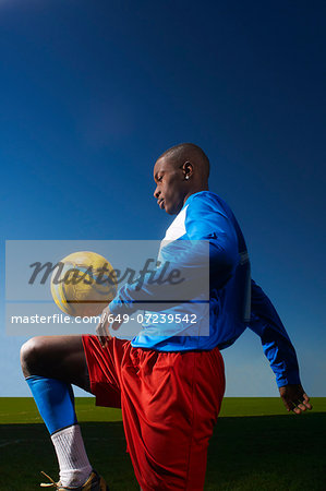 Young man playing keepy uppy with football