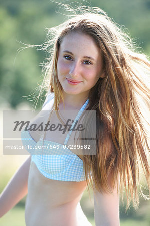Portrait of teenage girl wearing bikini top - Stock Photo - Masterfile