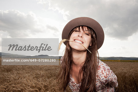 Mid adult woman with wheat in her mouth