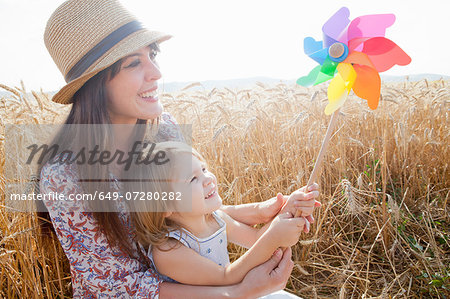 Mother and daughter in wheat field holding windmill