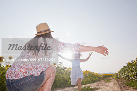 Girl running through field to mother with open arms Girl running through field to mother with open arms