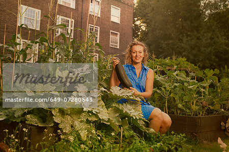 Young woman harvesting marrows on council estate allotment