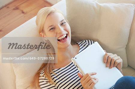 Young woman on sofa, using digital tablet