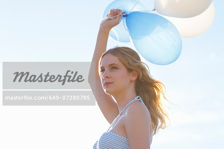 Portrait of young woman holding up balloons