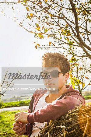 Portrait of young man leaning against haystack