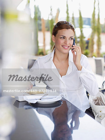 Young woman using mobile phone in outdoor hotel restaurant